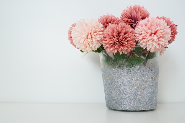 Bouquet di fiori artificiali di spugna rosa in un vaso d'argento grigio su sfondo bianco Opzione di decorazione d'interni di natura morta Arredamento della camera Spazio libero per il testo