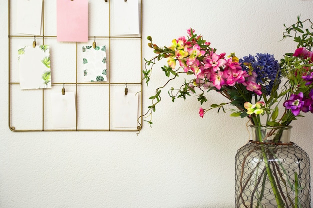 Bouquet di fiori colorati parete bianca e cartoline appese, interni moderni retrò