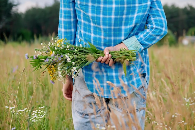 Bouquet di fiori di campo nelle mani di una donna nascosta dietro la schiena