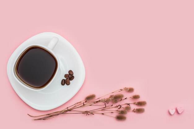 bouquet di fiori di campo secco con una tazza di caffè su sfondo rosa. Concetto di umore mattutino