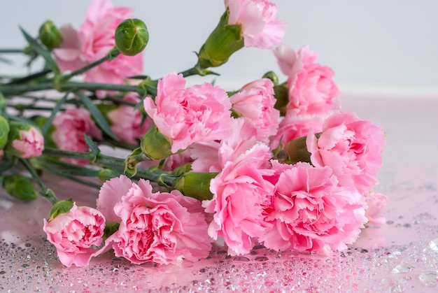 Bouquet di fiori di garofano rosa su un tavolo con gocce d'acqua