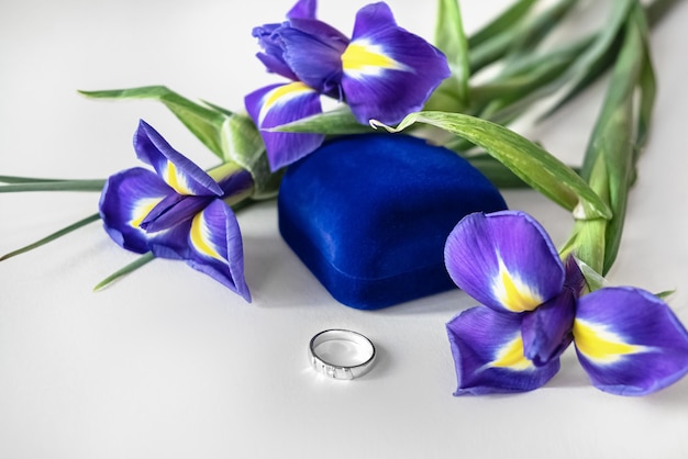 Bouquet di fiori di iris e anello di fidanzamento che si trova davanti alla confezione regalo di velluto blu
