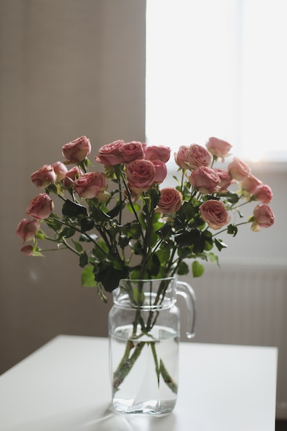 bouquet di fiori di rose rosa in vaso di vetro in un accogliente soggiorno