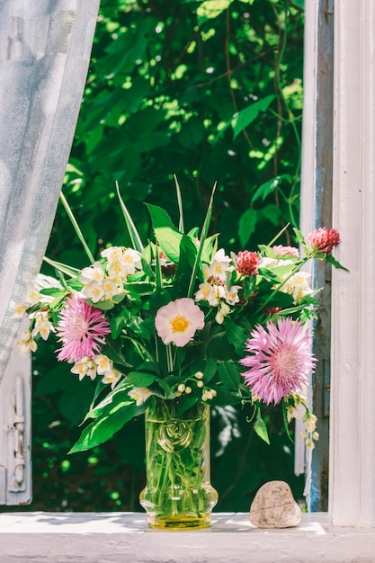 bouquet di fiori di trifoglio, fiordalisi e gelsomino in un vaso di vetro e una pietra a forma di cuore