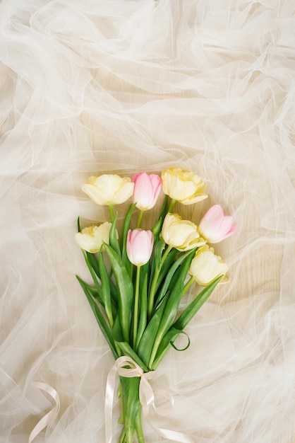 Bouquet di fiori di tulipano primaverile su sfondo di tessuto beige per la festa della mamma Disposizione piatta