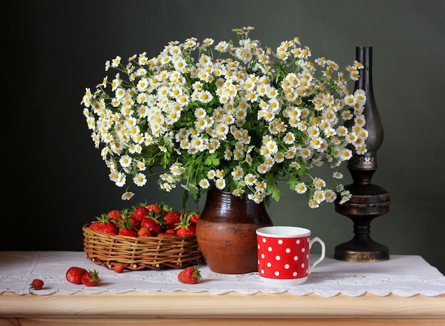 bouquet di fiori e frutti di bosco in un cesto su un tavolo con una tovaglia di pizzo.