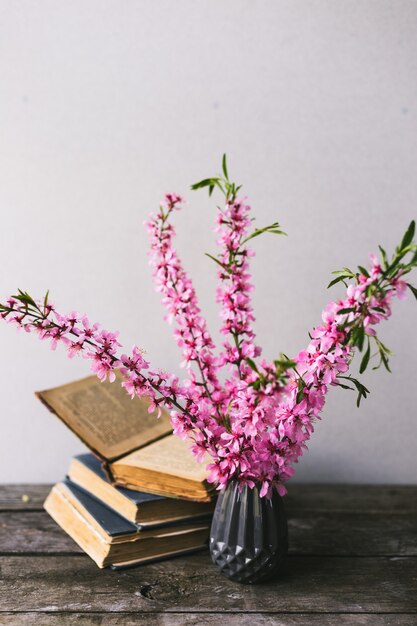 Bouquet di fiori e libri antichi su una vecchia tavola di legno con copia spazio. Arredamento vintage.