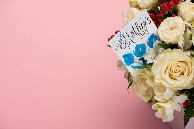 Bouquet di fiori in confezione regalo festiva con biglietto di auguri per la festa della mamma su sfondo rosa
