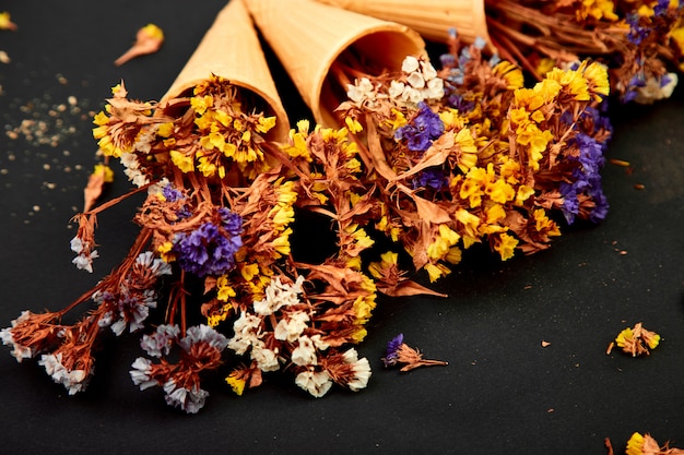 Bouquet di fiori in un cono di cialda su sfondo nero.