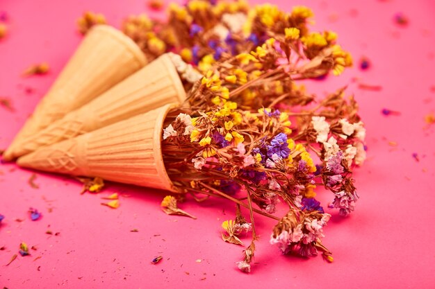 Bouquet di fiori in un cono di cialda su uno sfondo rosa.