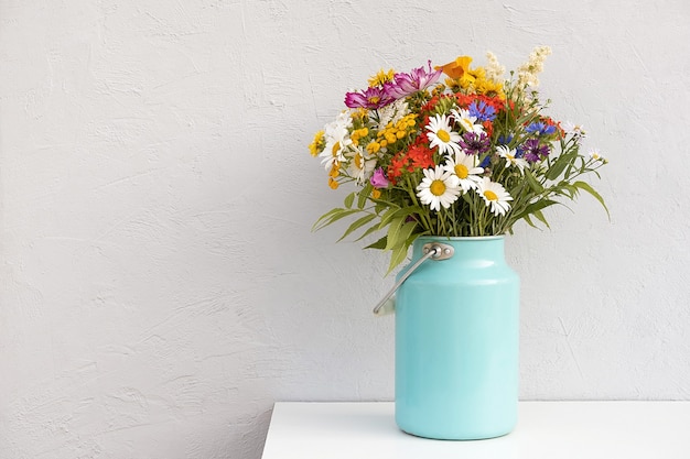 Bouquet di fiori luminosi in vaso di latta sul muro di pietra grigia di sfondo. Modello per cartolina. Concetto Festa della donna, Festa della mamma, Ciao estate o Ciao primavera.