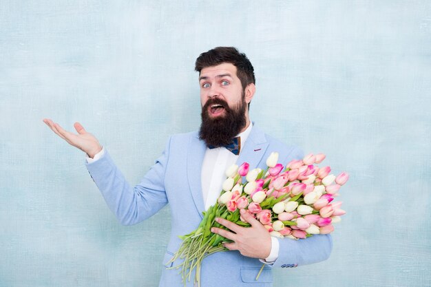 Bouquet di fiori per la festa della donna Uomo barbuto con tulipani Negozio di fiori Idee per celebrare l'atmosfera primaverile Data d'amore Bouquet regalo Hipster uomo barbuto con bouquet di fiori Concetto di auguri 8 marzo