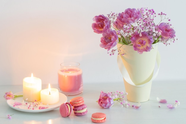 Bouquet di fiori primaverili rosa e candele accese sul tavolo bianco