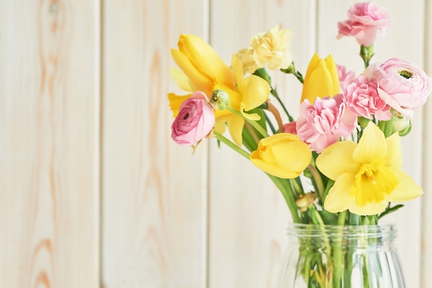 Bouquet di fiori primaverili: tulipani, garofani, ranuncoli e narcisi in vaso sul tavolo. Saluto festa della mamma