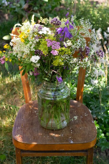 Bouquet di fiori selvatici in vaso di vetro su sedia in giardino