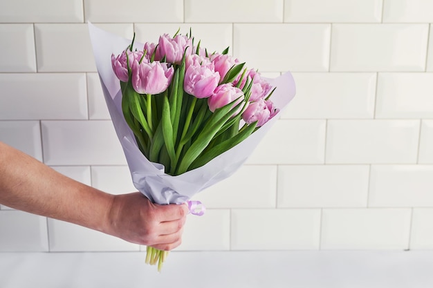 Bouquet di fiori tulipani rosa in mano Consegna fiori Buon compleanno Sfondo primaverile Festa della mamma