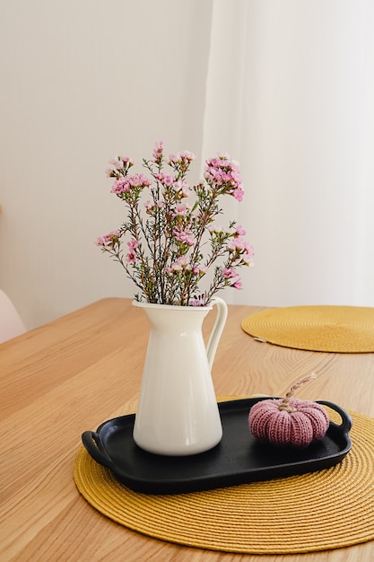 bouquet di fiori viola in una brocca bianca sul tavolo di legno.