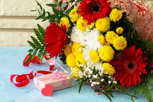 bouquet di gerbera con crisantemi con cuori e presente.