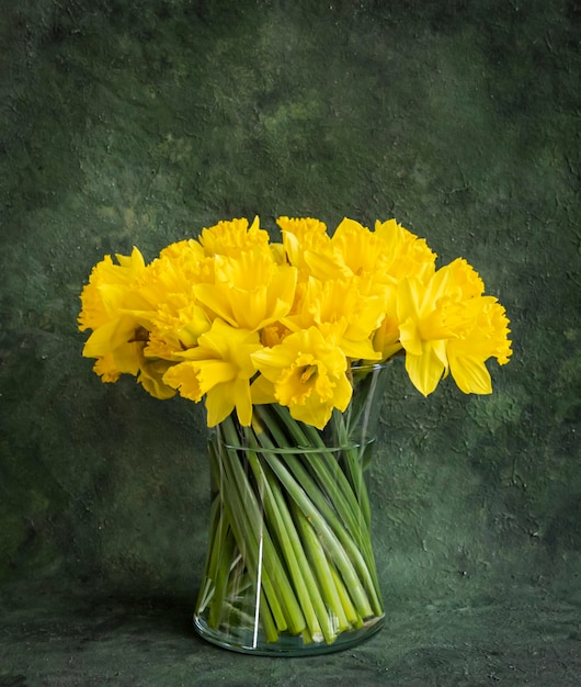 bouquet di graziosi narcisi in vaso di vetro su sfondo verde vintage