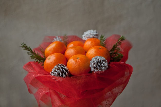 Bouquet di mandarini e rami di albero di Natale. Mazzo di frutta commestibile di Capodanno. Regalo per Natale. Regalo fai da te. regalo utile fatto di frutta. decorazione di coni e frutti di mandarino.