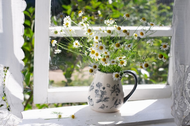 Bouquet di margherite sul davanzale. La finestra è aperta.