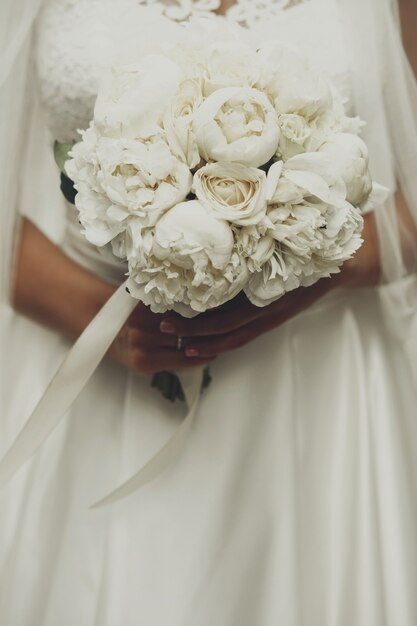 Bouquet di meravigliose peonie nelle teneri braccia della sposa