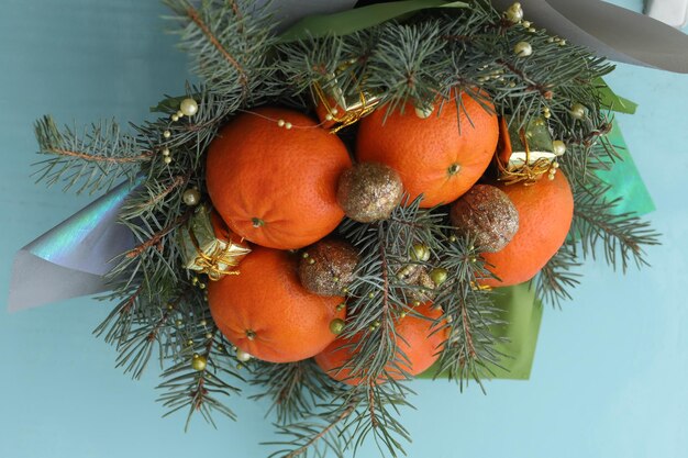 Bouquet di Natale di rami di abete mandarini e piccole scatole regalo su sfondo blu Capodanno