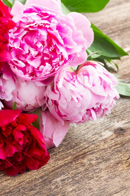 Bouquet di peonie rosse e rosa fresche sulla tavola di legno