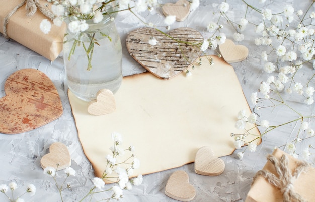 Bouquet di piccoli fiori bianchi e cuori di legno su uno sfondo grigio