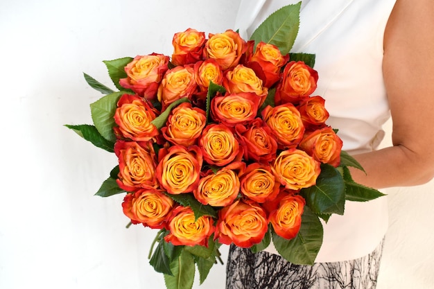 Bouquet di rose alte gialle fresche nelle mani della donna Bellissimi fiori freschi per la vacanza Donna con fiori d'arancio al chiuso