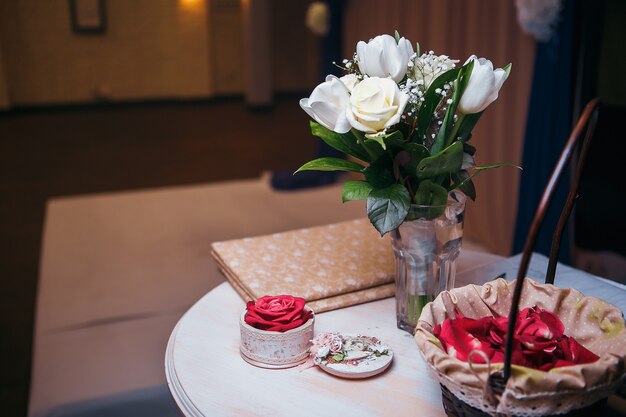 Bouquet di rose bianche in vaso di vetro su runner da tavolo grigio e tavolo da cucina.