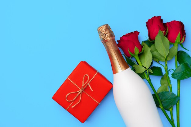 Bouquet di rose, bottiglia di champagne e confezione regalo vista dall'alto