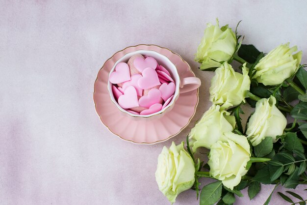 bouquet di rose chiare e cuori di raso in una tazza rosa