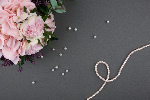 bouquet di rose con collana di perle su sfondo grigio