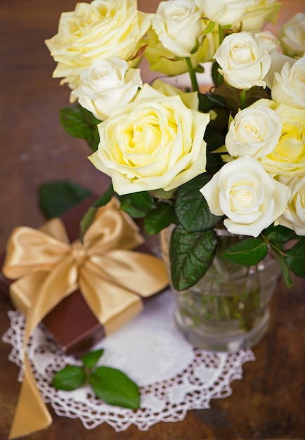 Bouquet di rose in fiore in vaso su uno sfondo di legno