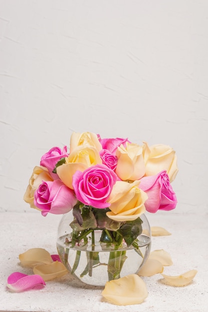 Bouquet di rose multicolori fresche in un vaso. Il concetto festivo per matrimoni, compleanni, 8 marzo, festa della mamma o San Valentino. Biglietto di auguri, sfondo chiaro