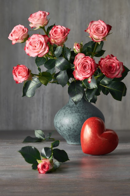 Bouquet di rose rosa e un cuore di pietra rossa sul buio