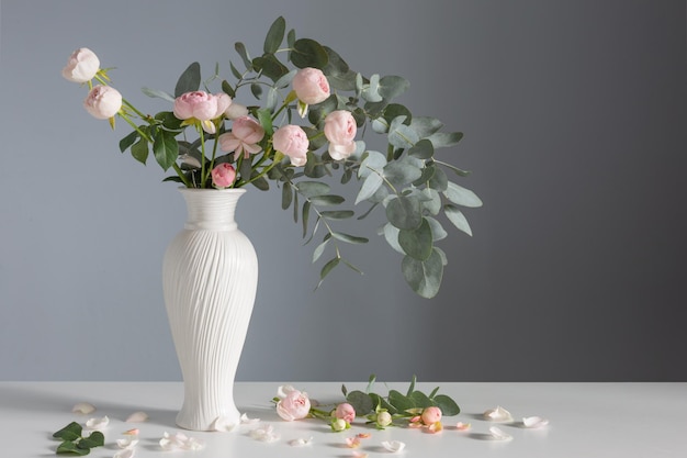 Bouquet di rose rosa in vaso di ceramica bianca su sfondo grigio muro