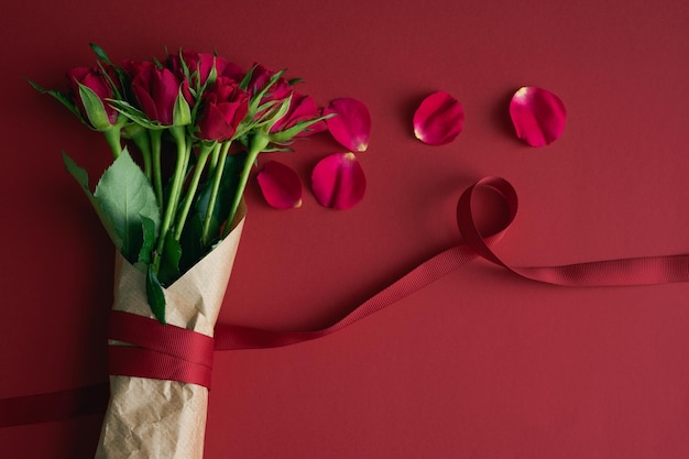 Bouquet di rose rosse con nastro decorativo su sfondo viola Copia spazio