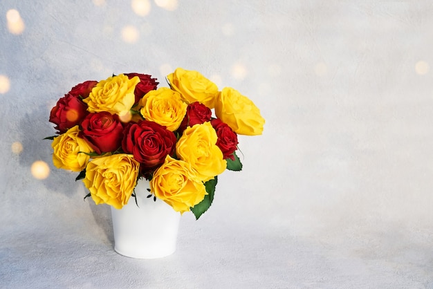 Bouquet di rose rosse e gialle in vaso bianco.