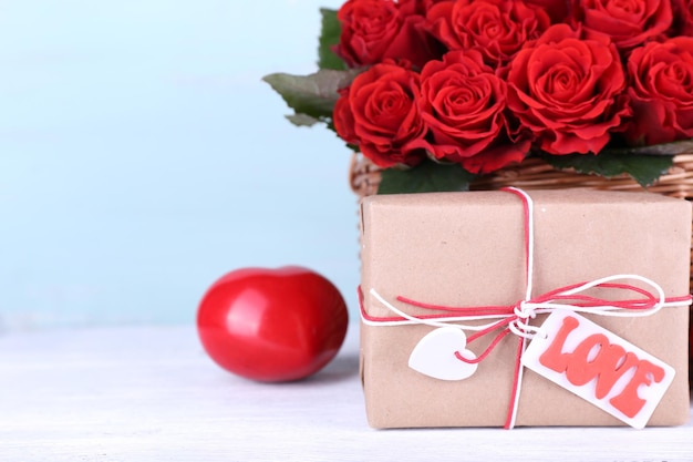 Bouquet di rose rosse in cestino con scatola presente su sfondo di legno