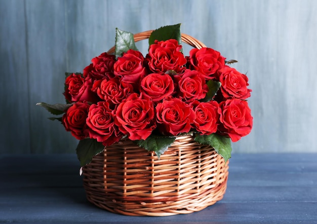 Bouquet di rose rosse in cestino su sfondo di legno