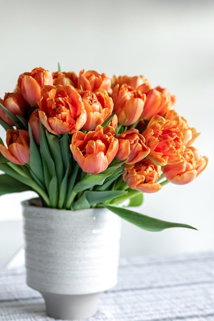 Bouquet di tulipani arancioni in un vaso su uno sfondo chiaro sfocato