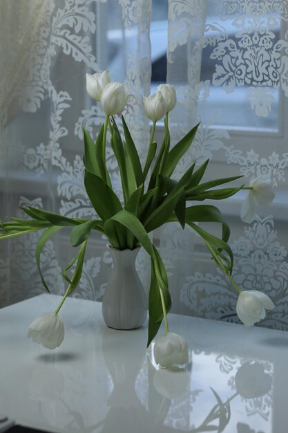 Bouquet di tulipani bianchi in un vaso sul tavolo vicino alla finestra