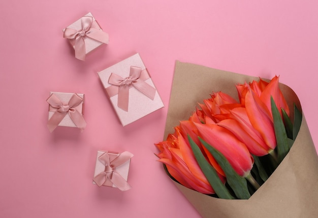 Bouquet di tulipani con scatole regalo su pastello rosa