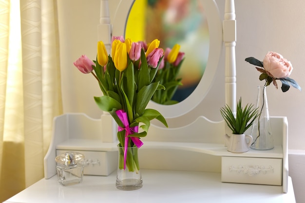 Bouquet di tulipani multicolori in un vaso sulla toletta bianca in una stanza luminosa