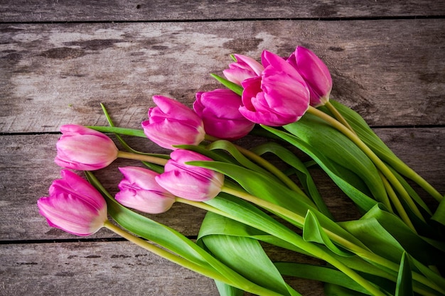 Bouquet di tulipani rosa brillante su uno sfondo di legno rustico