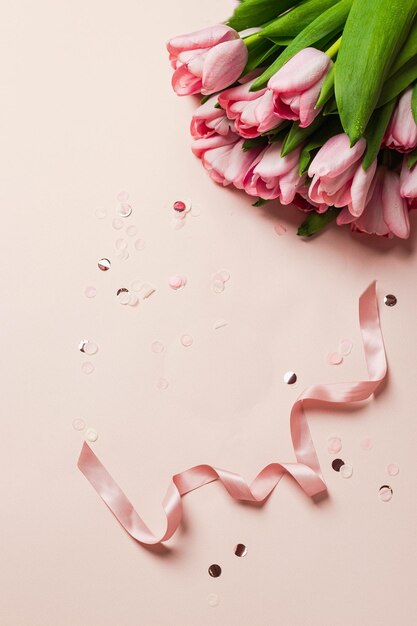 Bouquet di tulipani rosa con nastro rosa e coriandoli su sfondo rosa. flatlay con copyspace. concetto di biglietto di auguri