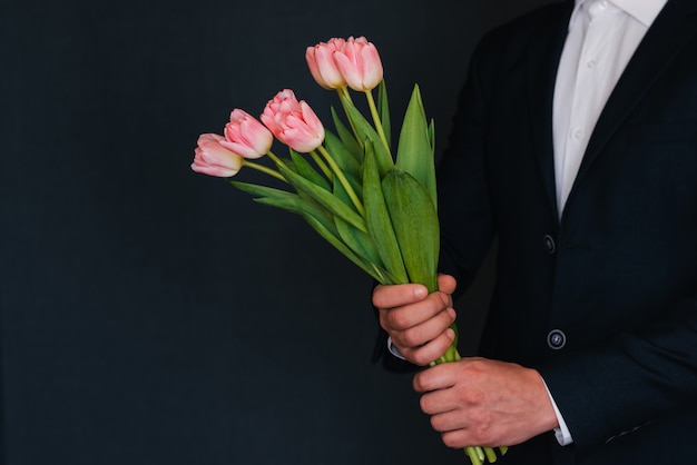 Bouquet di tulipani rosa nelle mani degli uomini in un vestito