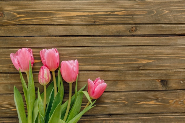 Bouquet di tulipani rosa su sfondo di legno marrone Spazio per la copia vista dall'alto